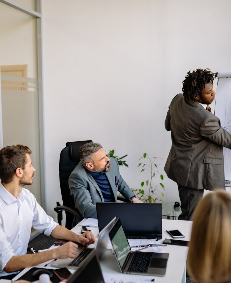 Diverse team explaining workflow with charts on a whiteboard